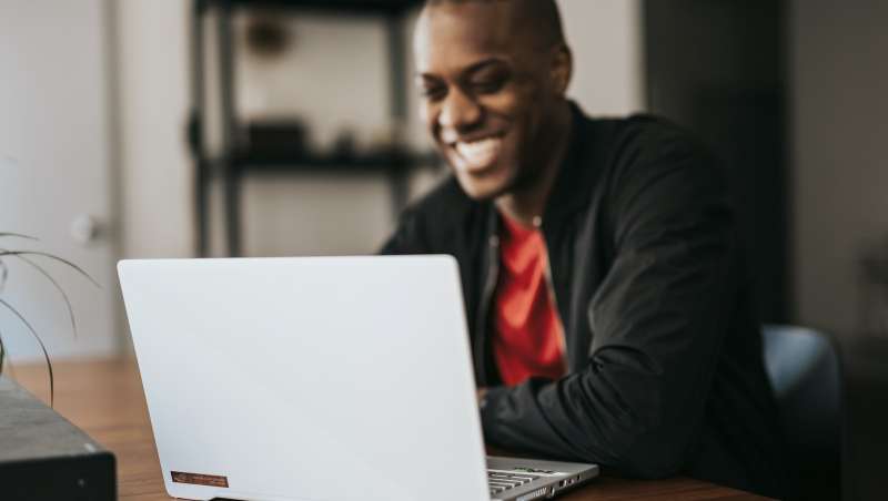 man in black blazer sitting by the table with laptop
